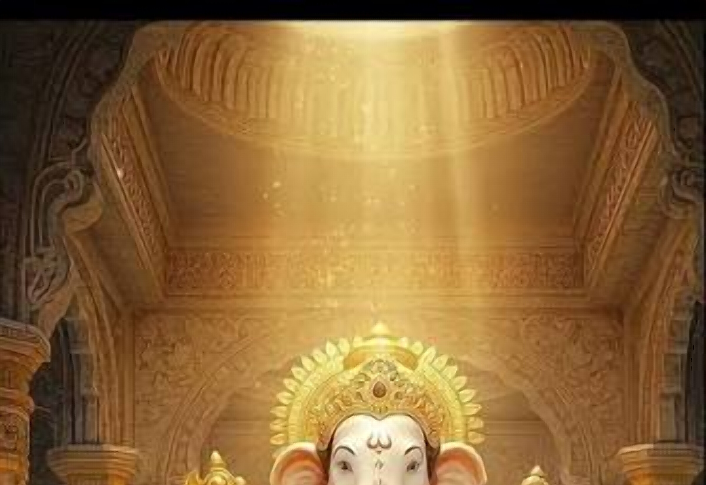 A golden Ganpati idol seated among flowers and greenery